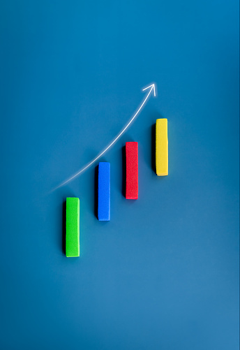 Rising up arrow on vertical multicolor block sticks as a business chart on blue background, minimal style. Business goal and success, profit, income, growth marketing, and trend concepts.