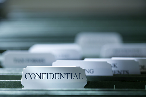 A file folder containing confidential documents photographed with a very shallow depth of field.