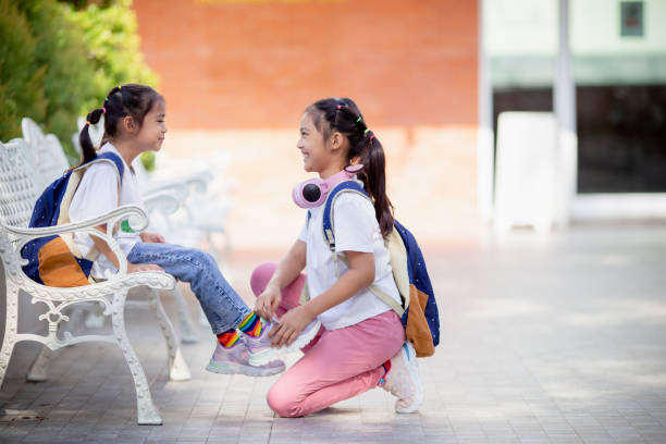 学校に戻る。かわいい女の子の優しさは、友達のために靴ひもを結びます。 - child 6 7 years education school ストックフォトと画像