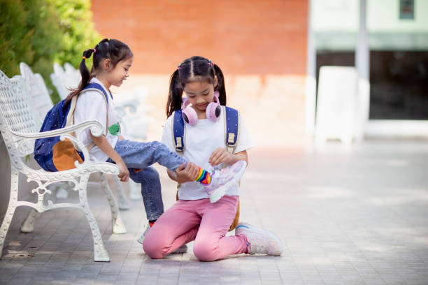 学校に戻る。かわいい女の子の優しさは、友達のために靴ひもを結びます。 - child 6 7 years education school ストックフォトと画像