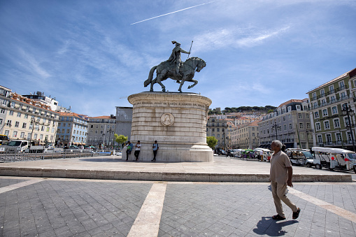 Lisbon, Portugal - Street view of Baixa district on a summer afternoon. Equestrian statue of King John I and tuk-tuks and people in the Praça da Figueira.