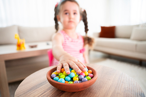 cute baby girl eating colorful candies. Baby girl eating unhealthy colorful candies. A plate of colorful marshmallows