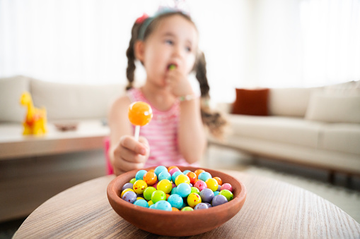 cute baby girl eating colorful candies. Baby girl eating unhealthy colorful candies. A plate of colorful marshmallows