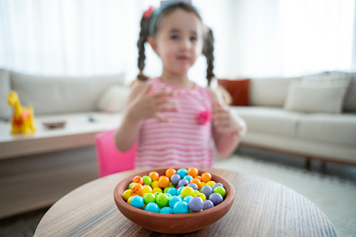 cute baby girl eating colorful candies. Baby girl eating unhealthy colorful candies. A plate of colorful marshmallows