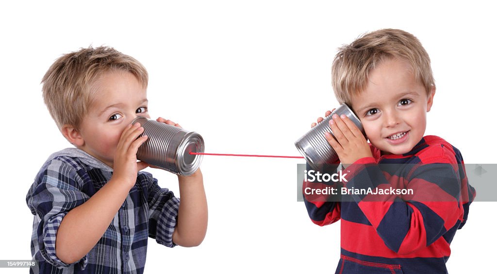 Two young boys using tin cans and a string as a telephone Little boy playing with can phone connected by string, concept for talking to yourself Child Stock Photo