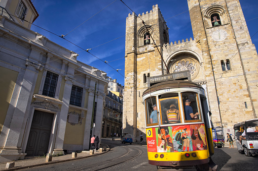 Lisbon, Portugal - Street view of Alfama district on a summer afternoon. A yellow Tram in front of Se Cathedral.