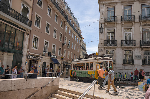 Lisbon, Portugal - Street view of Baixa district on a summer afternoon. A yellow Tram and people can be seen.