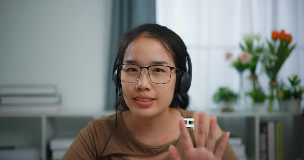 istock Young Asian woman wearing glasses using a laptop on a desk 1550003216