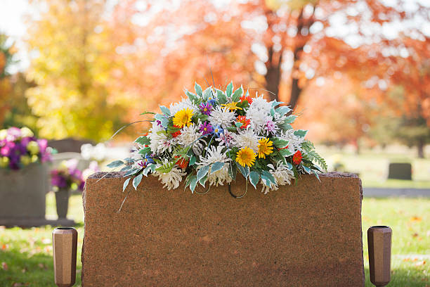 Colorful Tombstone Boquet A colorful spray of flowers grace the top of a tombstone in the fall. cemetery stock pictures, royalty-free photos & images