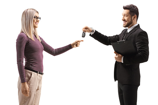 Businessman giving car keys to a young woman isolated on white background