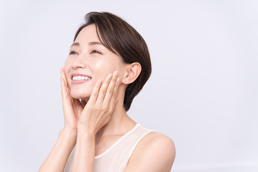 Skin care. An asian woman with beauty face is  touching healthy facial skin.