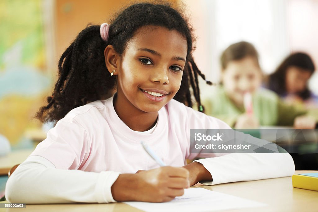 Garota escreve no bloco de notas em sala de aula. - Foto de stock de Afro-americano royalty-free