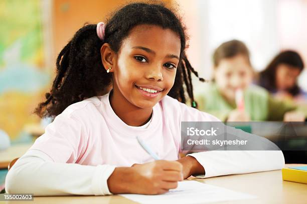 Foto de Garota Escreve No Bloco De Notas Em Sala De Aula e mais fotos de stock de Afro-americano - Afro-americano, Aluna, Aluno de Primário