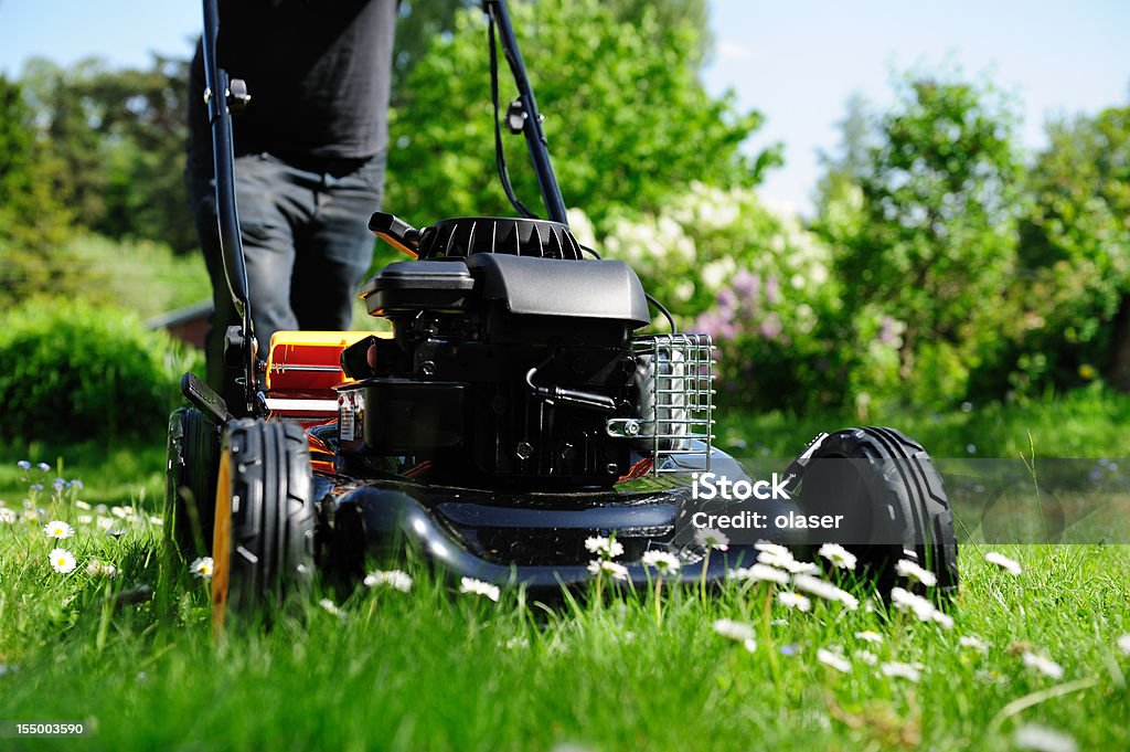 Mowing o gramado em nice green garden - Foto de stock de Cortador de grama - Equipamento de jardinagem royalty-free