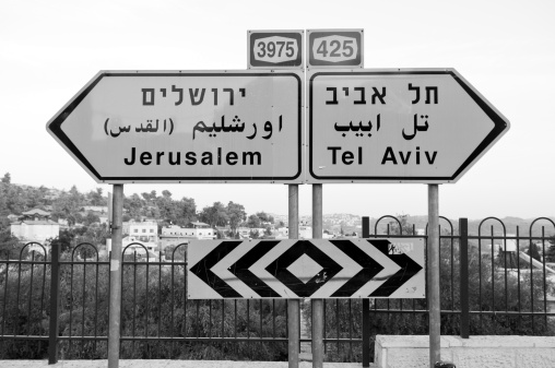 Black and white photograph of a road sign in Israel pointing the opposite directions to Jerusalem and Tel Aviv.