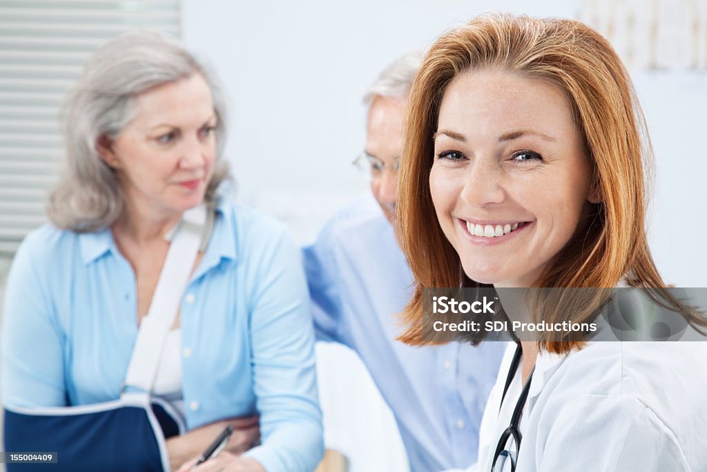 Sorridente Jovem médico no escritório com paciente e cônjuge - Royalty-free Ferido Foto de stock