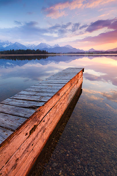 istock tranquil sunset at lake hopfensee, bavaria with jetty, boat, germany 155005821