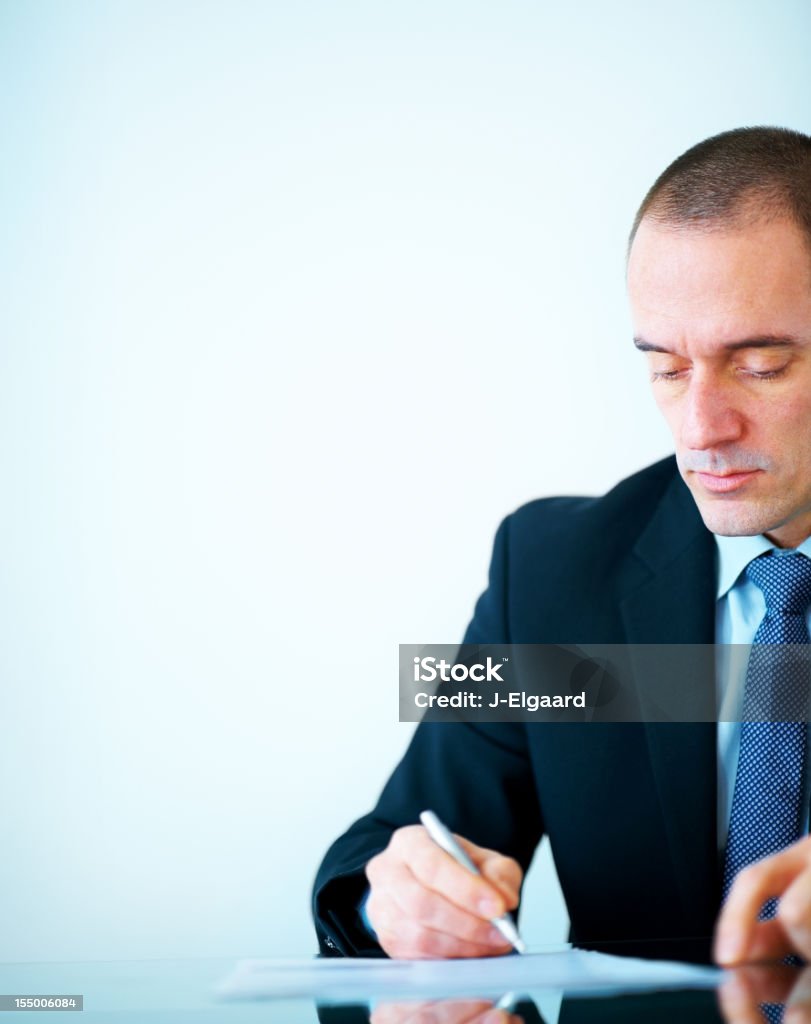 Empresario escribiendo algo en papel en la oficina - Foto de stock de Contrato libre de derechos