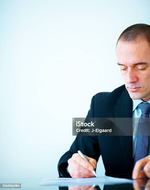 Empresario Escribiendo Algo En Papel En La Oficina Foto de stock y más banco de imágenes de Contrato - Contrato, Firmar, Adulto