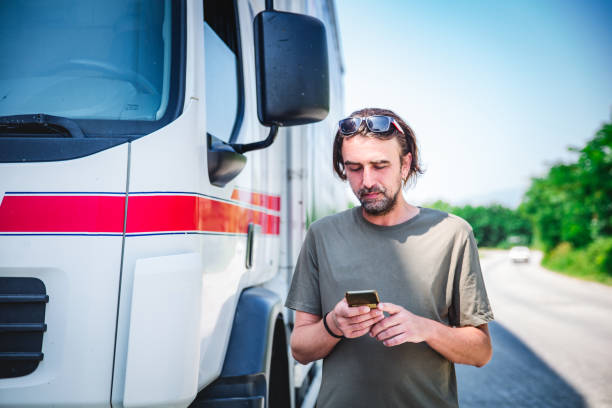 chauffeur de camion regardant un téléphone - semi truck truck red truck driver photos et images de collection