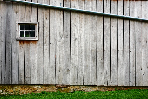 Wood barn side with one window and beautiful stone work.
