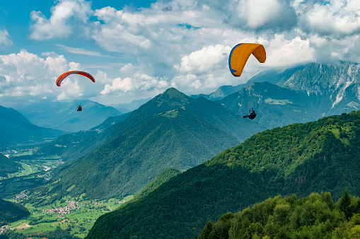 2022-08-12, Tolmin, Slovenia. Colorful paraglider wings fly in the mountains near Tolmin, Slovenia. Soca valley, the Europe popular tourist destination, Mecca for extreme sports and active lifestyle.