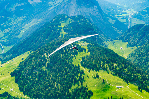 Brave hang glider pilot soar in the mountains in Austrian Alps in Diedams. Extreme sports in European Alps
