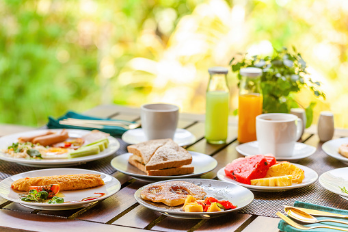 Morning breakfast at tropical outdoor restaurant in Asian resort. Enjoy a tasty and nutritious meal with pancakes, tropical fruit, and a glass of orange juices. Concept of a Thailand vacation.