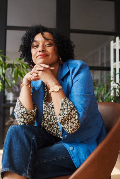 Mature creative business woman sitting with a smile. Stock photo Close up shot of a mature businesswoman sitting in her off with her hands under chin while smiling. Stock photo woman sitting cross legged in chair stock pictures, royalty-free photos & images
