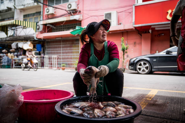 A vendor washes fish at a wet market in Bangkok. Daily life in Bangkok, Thailand on July 17, 2023.
