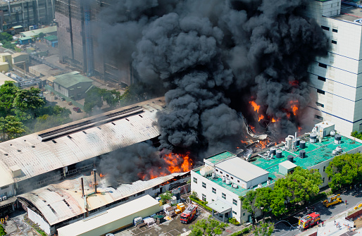 Aerial view of Fire in industrial building. Multi-storey concrete hangar with flames. Factory emergency concept.