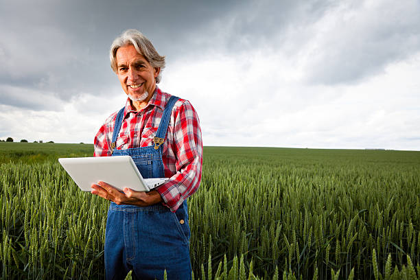 agricoltore suo raccolto di vendita su internet - farmer laptop selling internet foto e immagini stock