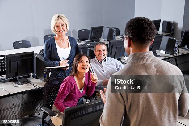 Foto de Adulto Alunos Ouvindo O Instrutor Em Um Computador De Sala De Aula e mais fotos de stock de Biblioteca de Informática