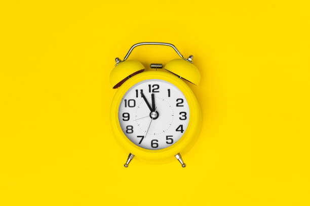 istock Yellow classic desktop clock the yellow background 1550137590