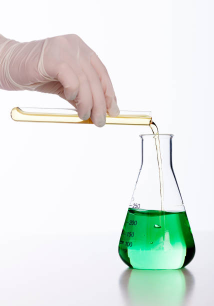 istock Gloved hand pours liquid into flask against white background 155013766
