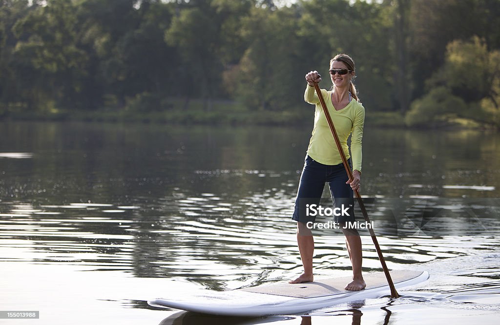 Athletic Woman Stehpaddeln auf den ruhigen See des Mittleren Westens. - Lizenzfrei Paddelbrett Stock-Foto