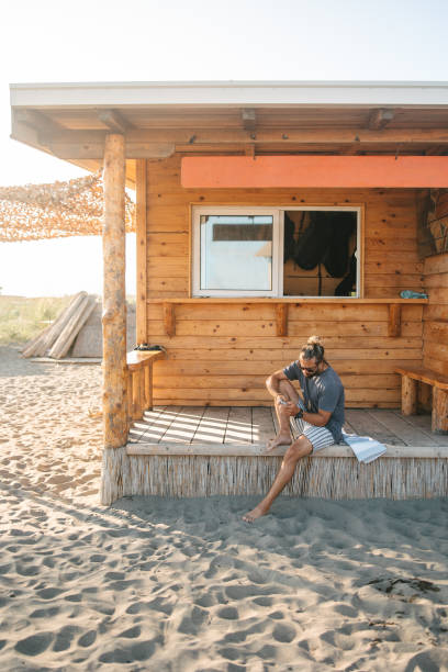 Man sitting in front of a log cabin and typing