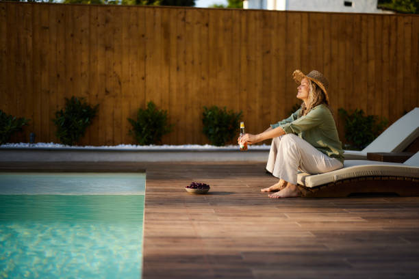 istock Smiling woman relaxing by the pool in the backyard. 1550141893