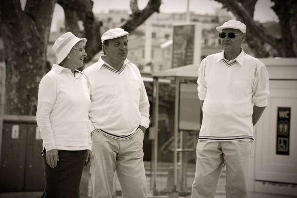 Three seniors standing on a promenade at the harbor of Cannes, France. \n\nShot at the iStockalypse in Cannes 2010. Processed in monochrome style with slight sepia toning to achieve vintage look like the image could have been taken in the 1950s