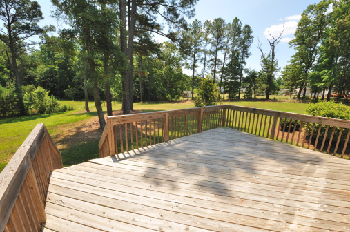 The decking boards of a porch with white railings in a suburb house