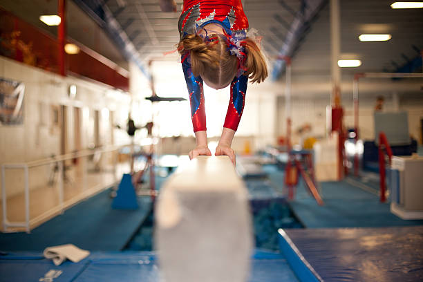 Young Gymnast Doing Handstand on Balance Beam stock photo