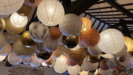 An assortment of paper lights hanging from a ceiling