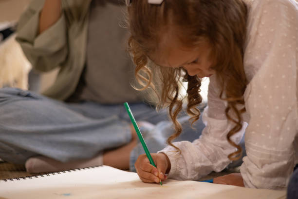 istock Cute girl drawing in a notebook at home. 1550158076