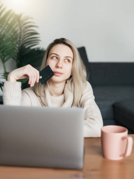 istock Young woman holding credit card and using laptop computer. 1550160231