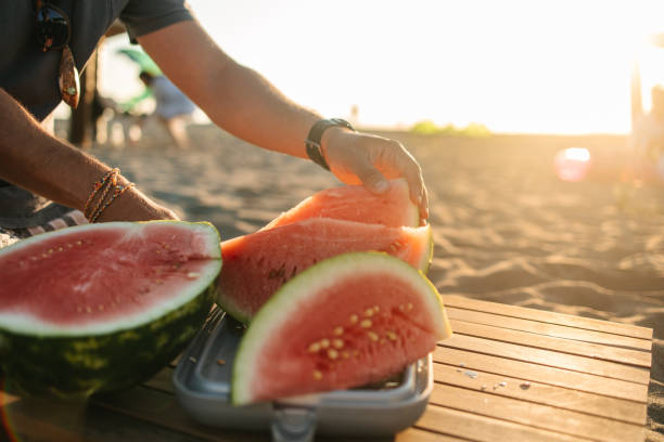 istock Man cutting watermelon on the beach 1550161791