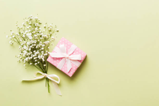 istock Gift or present box and flower gypsophila on light table top view. Greeting card. Flat lay style with copy space 1550169853