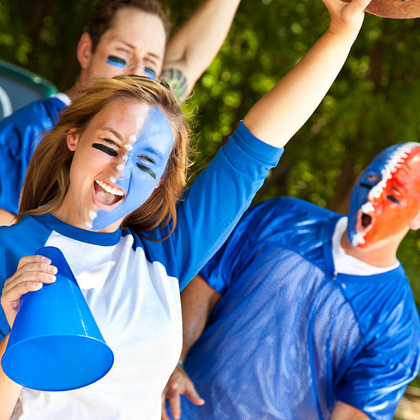 istock Screaming Fans With Faces Painted Showing Spirit at Tailgate Party 155017622