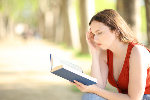 Worried book reader in a park