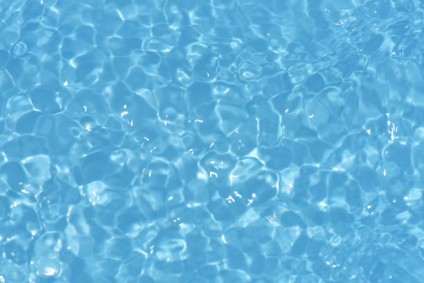 istock Blue water with ripples on the surface. Defocus blurred transparent blue colored clear calm water surface texture with splashes and bubbles. Water waves with shining pattern texture background. 1550199384