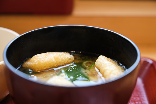 Japanese miso soup with kitsune tofu and wakame seaweed at a restaurant.